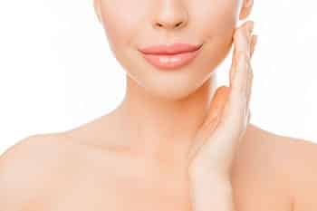 A woman touching her own face in relation to a facial rejuvenation treatment.