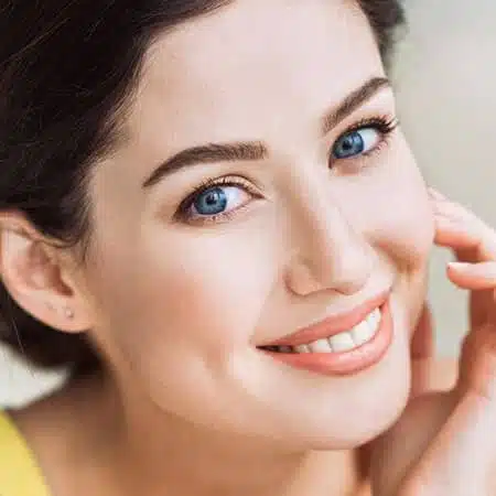 A pretty-looking female patient smiling after a brow lift procedure