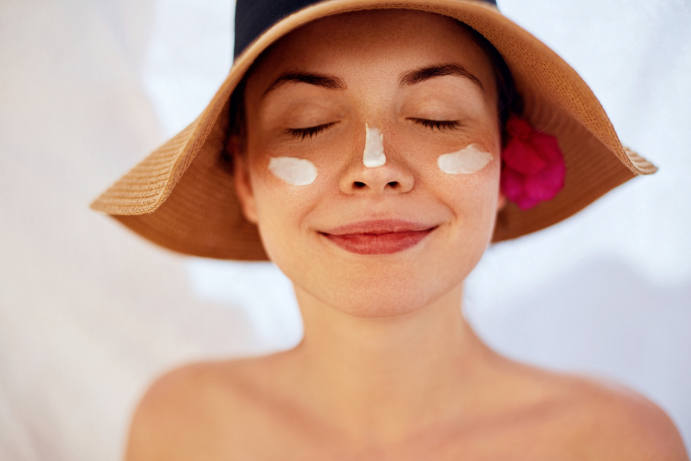 Woman wearing sun hat and sunscreen, protecting skin after Botox treatment to avoid UV-related inflammation.